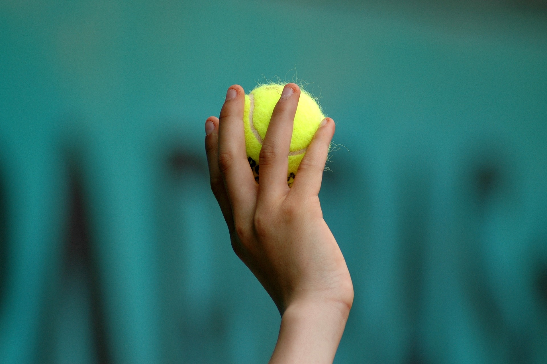 Die Hand eines Kindes hält einen Tennisball