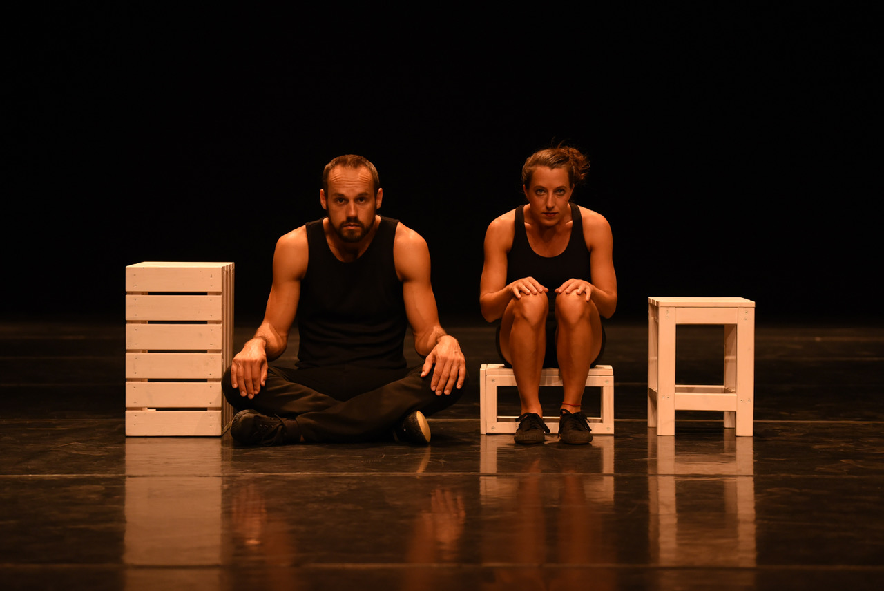 Ein Mann und eine Frau sitzen nebeneinander zwischen Holzkisten