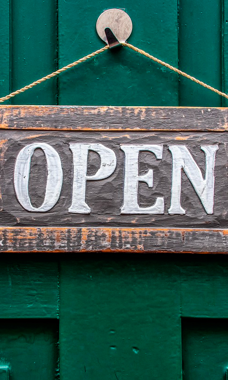 An einer grünen Tür hängt ein Schild mit der Aufschrift "open".