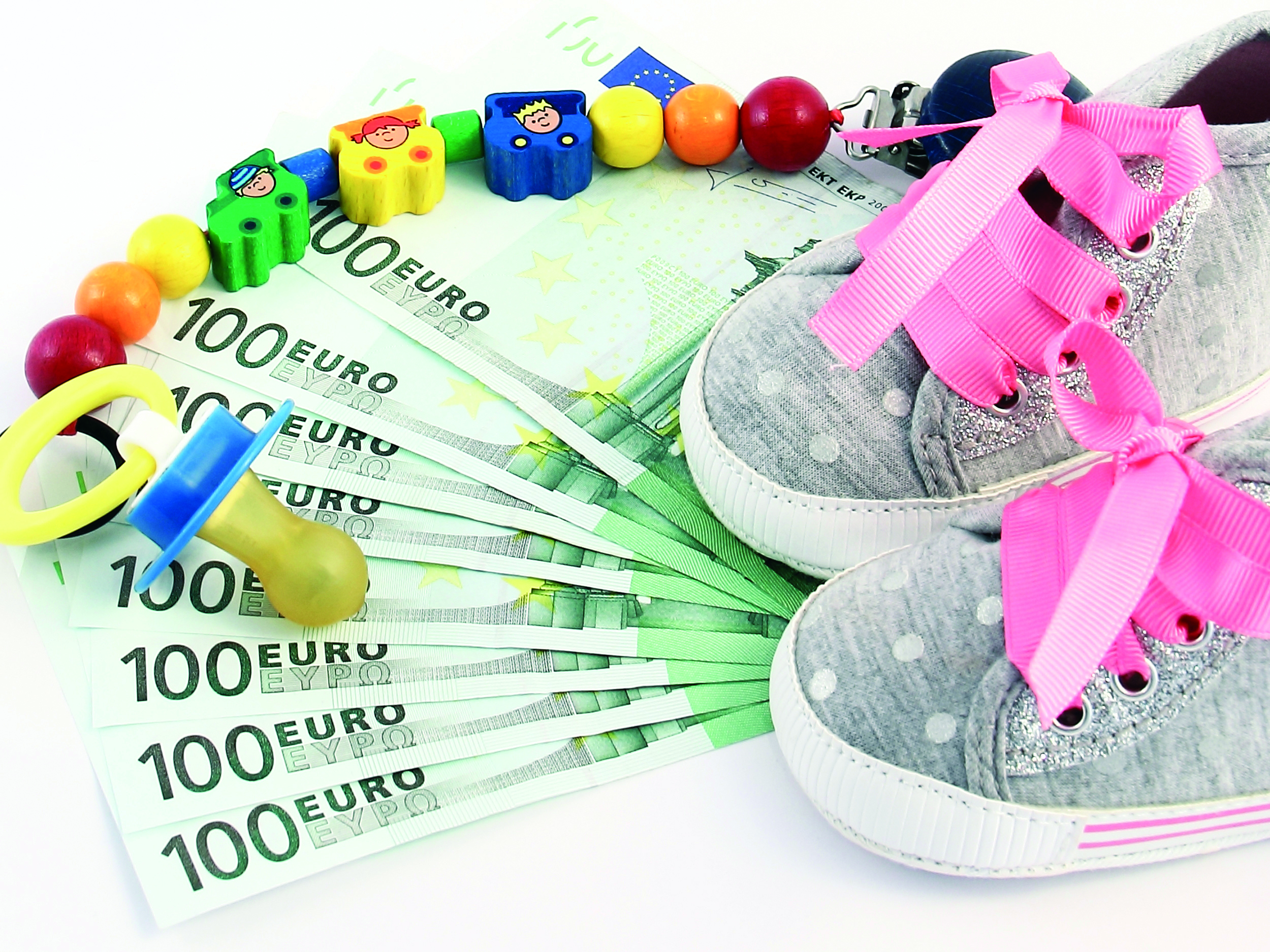 Auf mehreren Hundereuroscheinen liegen Babyschuhe und Schnuller