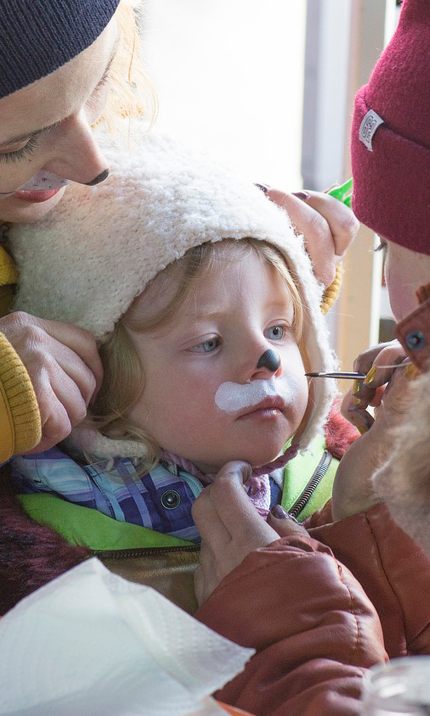 Eine Frau schminkt das Gesicht eines Kindes.