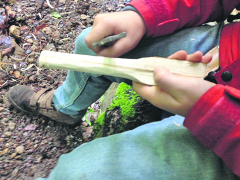 Junge schnitzt an einem stock