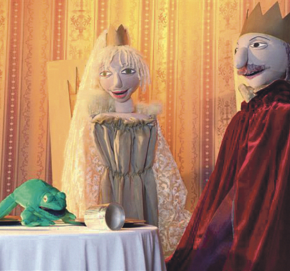 Auf einem Tisch sitzt ein Frosch, davor liegt die Krone. Daneben stehen König und Prinzessin.