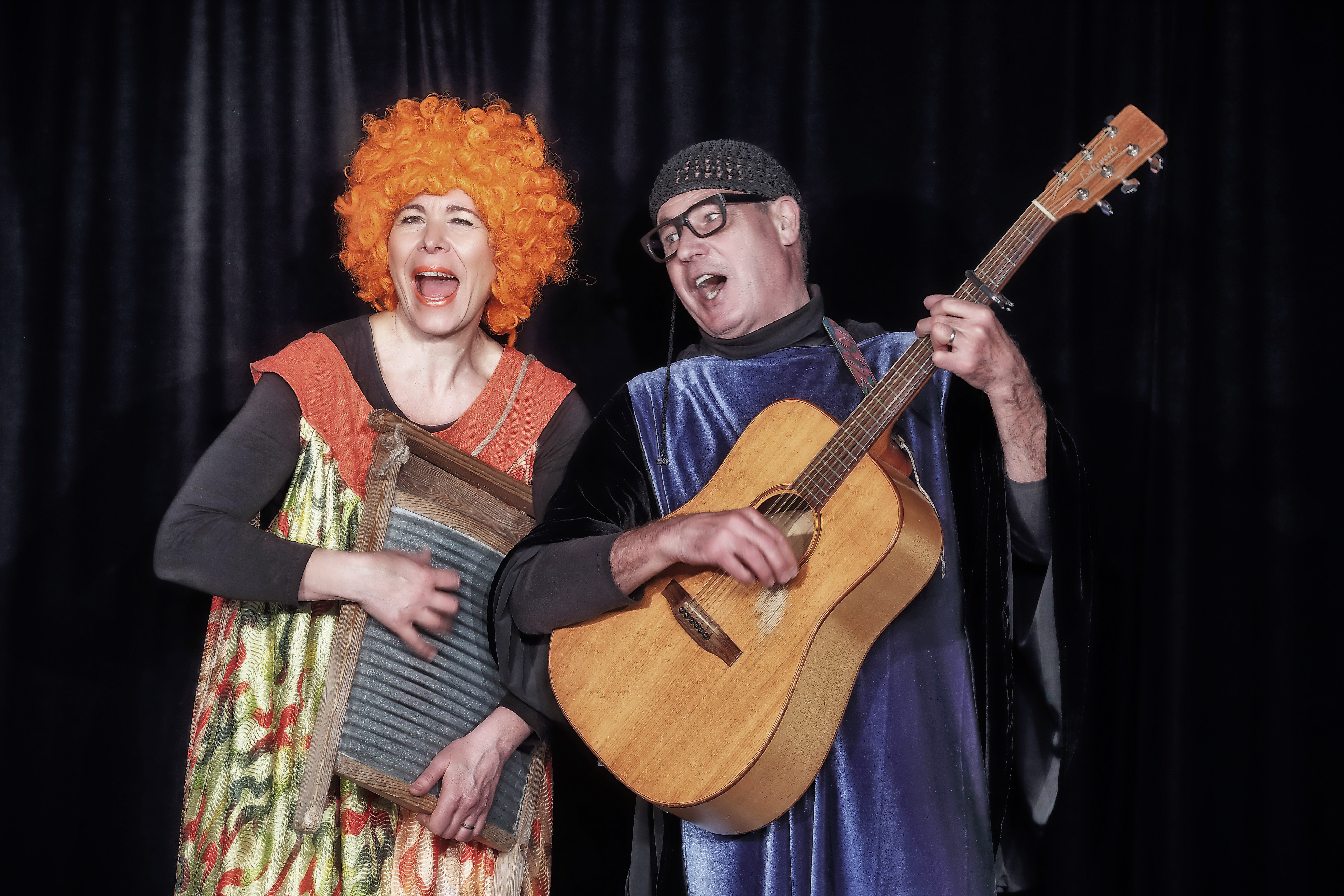 Ein Mann und eine Frau sind verkleidet und singen. Der Mann spielt Gitarre.