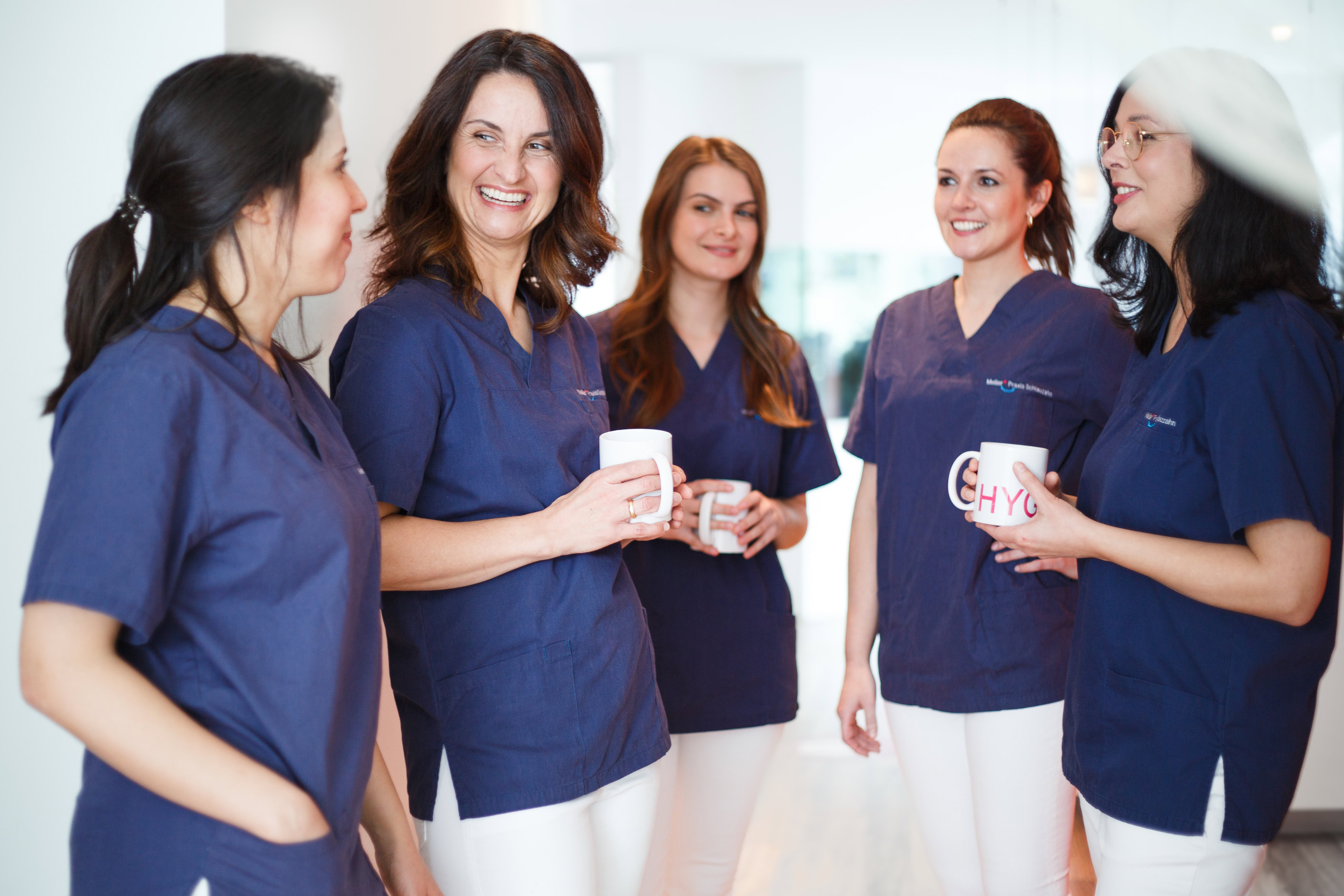 Fünf junge Frauen in medizinischer Bekleidung mit kaffetasssen in der Hand