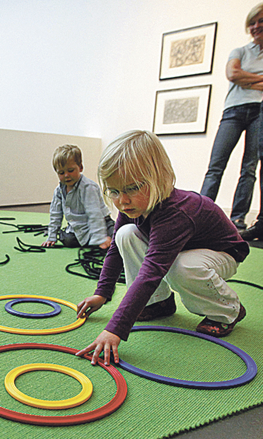 Zwei Kinder knien auf dem Boden und legen Kreise.