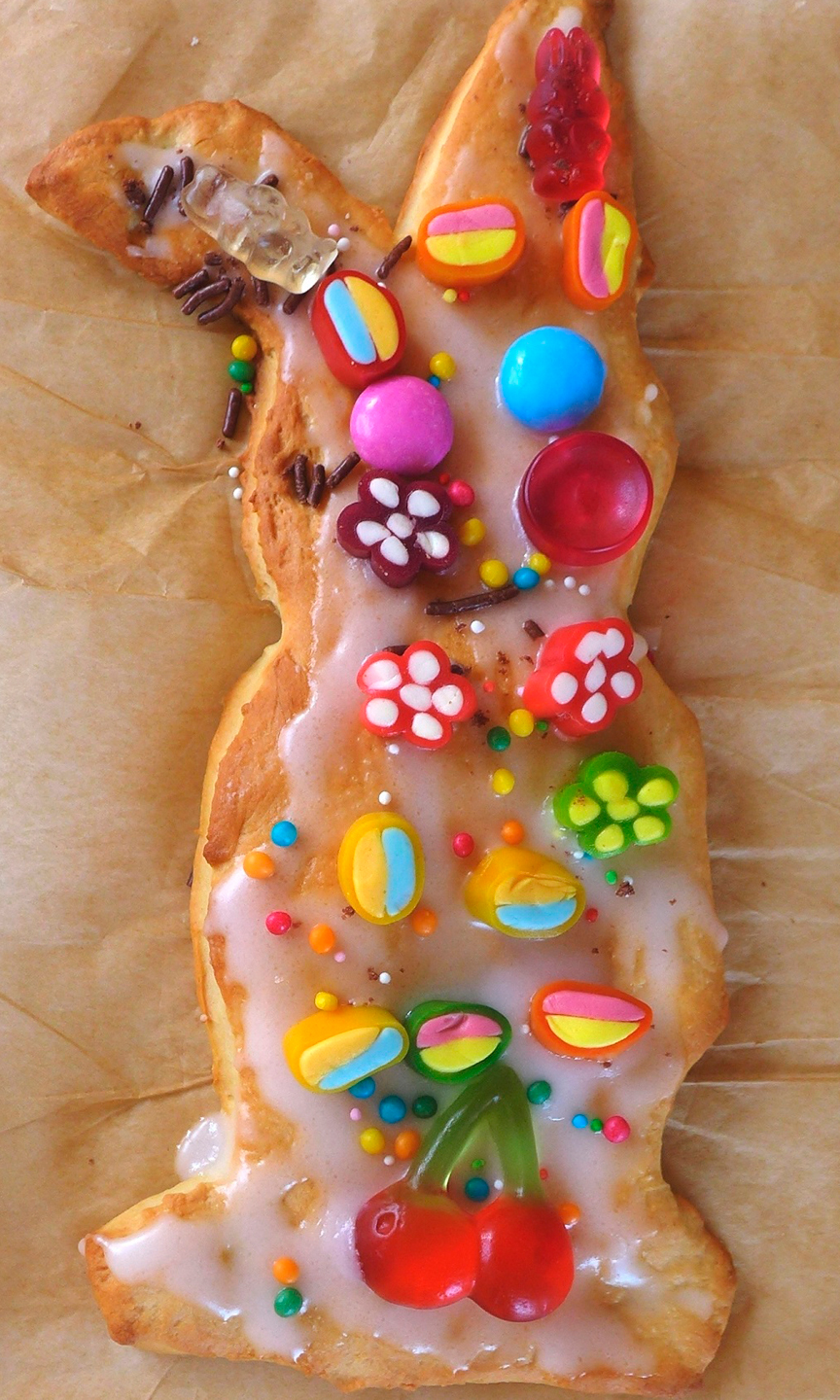 Keks in Hasenform auf Backpapier. Der Hase ist bunt verziert.