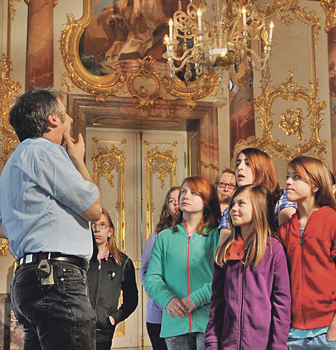 Kinder im Schloss hören einem Mann zu