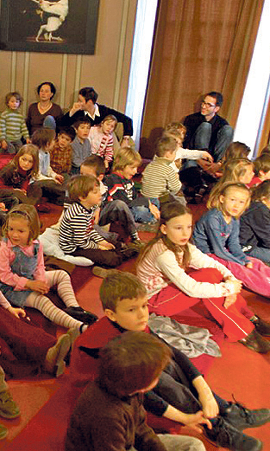 Eine Gruppe von Kindern sitzt auf Sitzkissen auf dem Boden.