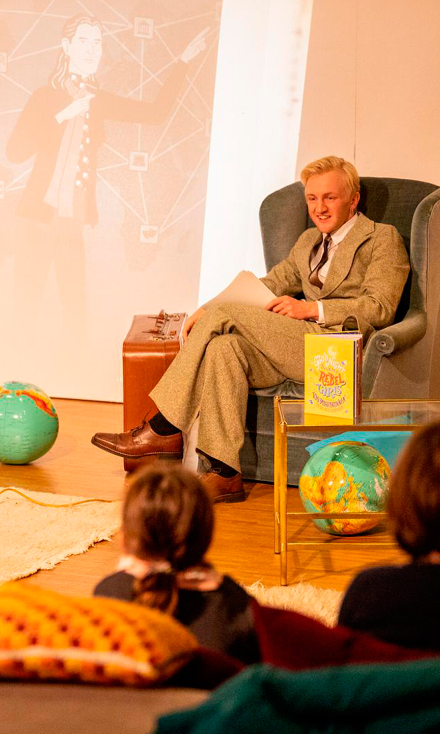 Mann im Anzug mit blonden Haaren sitzt in einem Sessel.