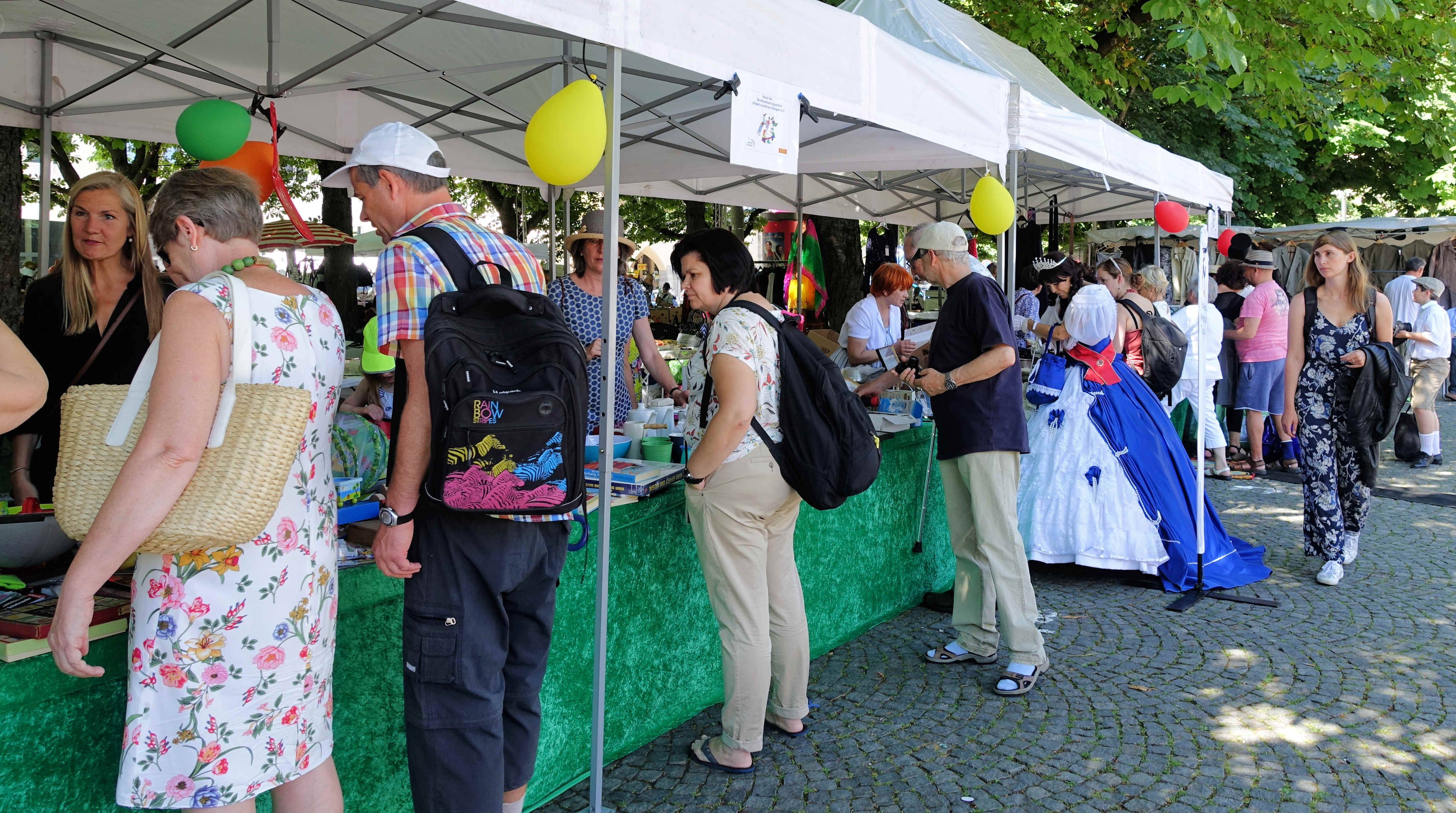 Vor einem Flohmarktstand stehen Besucher und Besucherinnen und stöbern