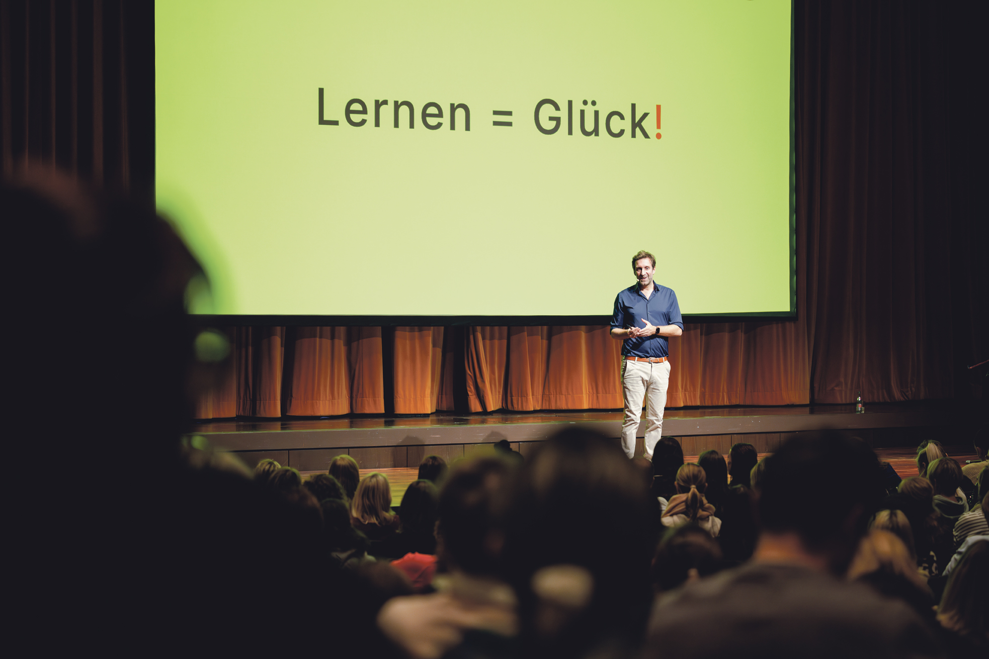 Mann steht auf der Bühne vor einem Publikum