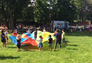 Kinder spiele mit einem großen, bunten Tuch.