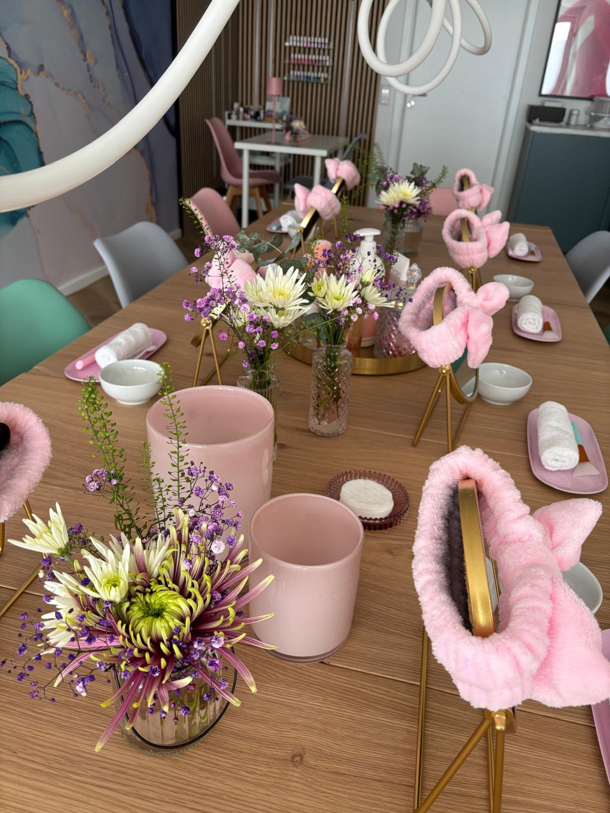 Schminksachen in Rosa stehen auf einem Holztisch.