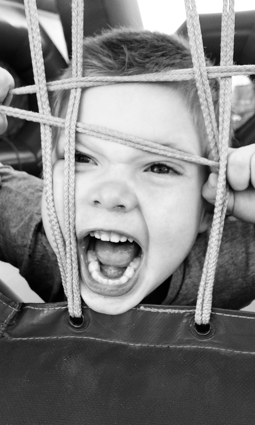 Junge schaut durch ein Netz und hat den Mund zu einem Schrei geöffent.