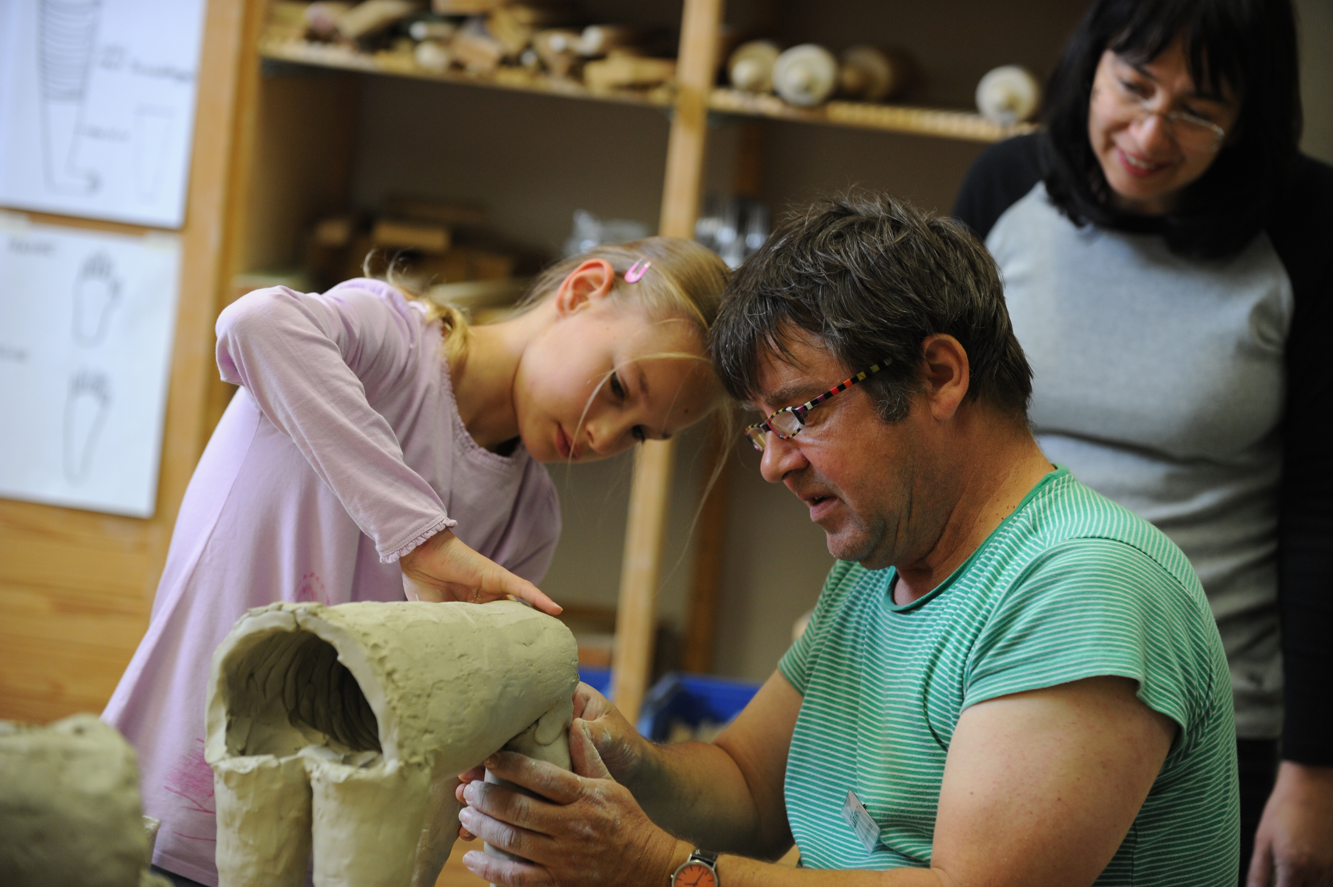 Ein Mann und ein Mädchen formen einen Figur aus Ton.
