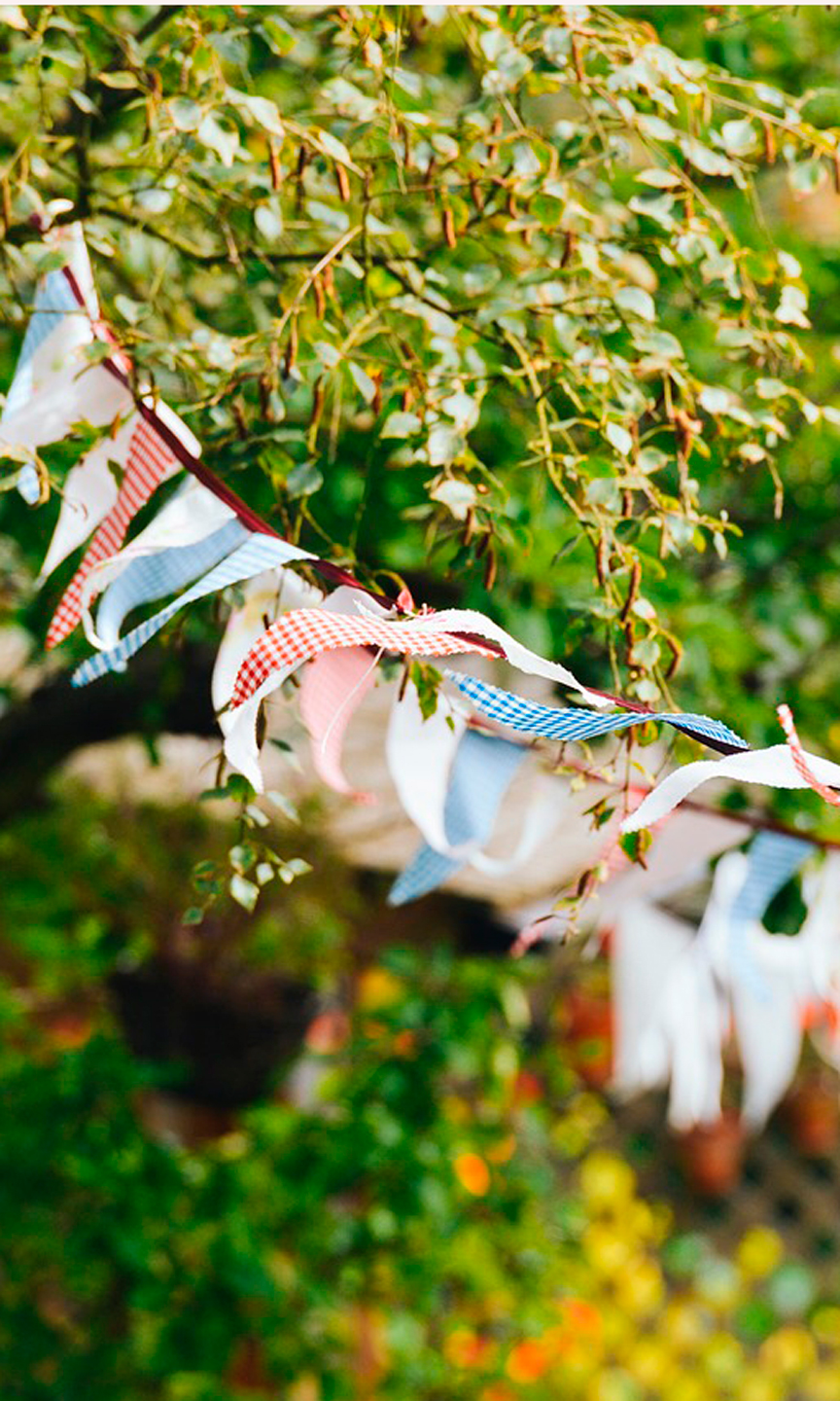 Bunte Wimpelkette hängt im Grünen.