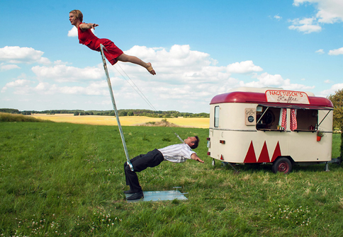 Eine Frau wird von einem Mann in die Luft gehoben mittels einem Stab.