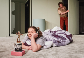 Junge Frau liegt auf dem Bauch am Boden und sieht verträumt eine Elvis-Statue an.