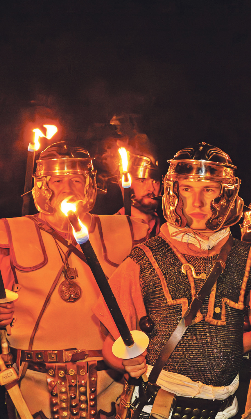 Gruppe von Männern, die als Römer verkleidet sind und Fackeln tragen.
