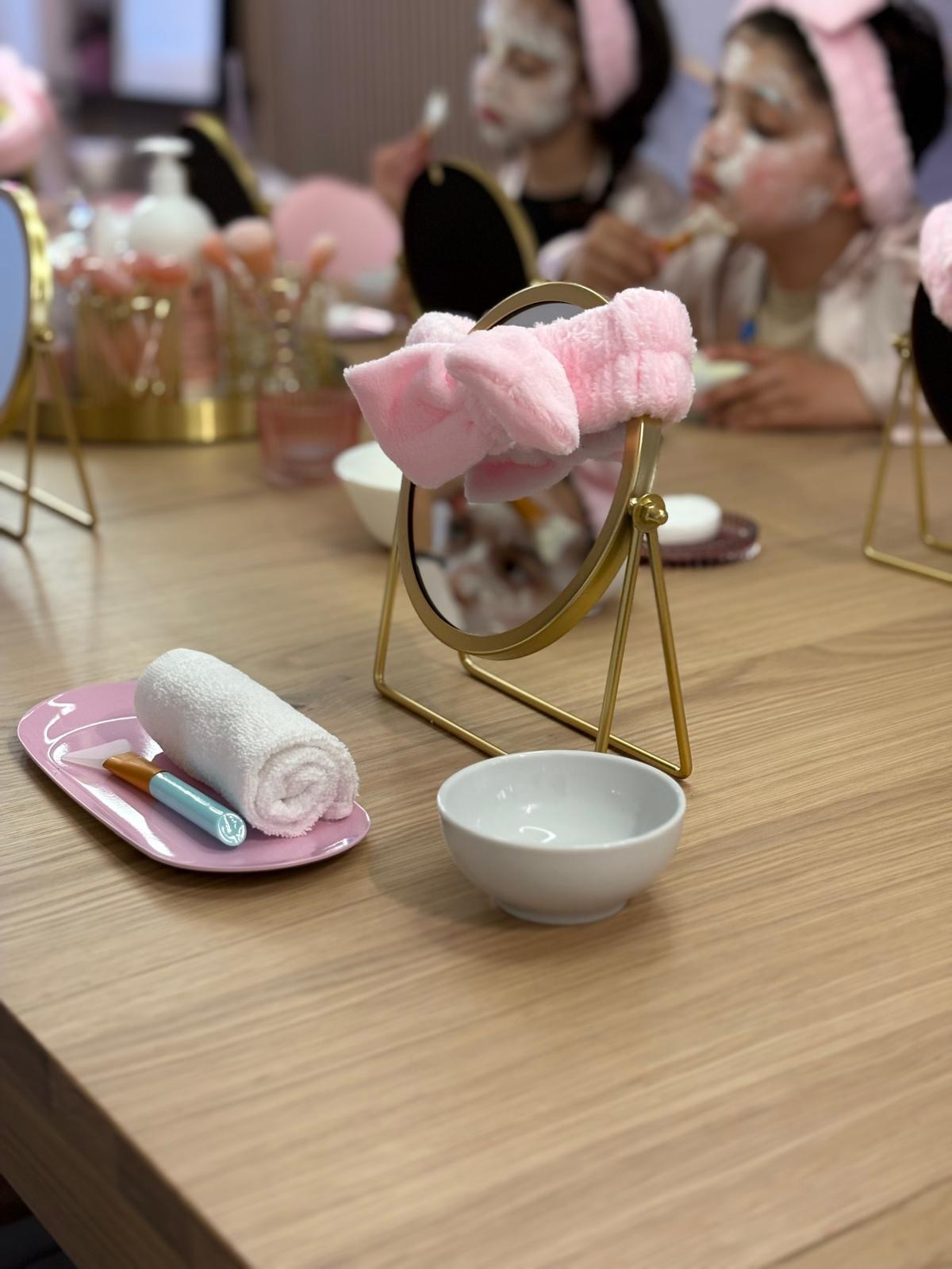 Detailaufnahme eines Kosmetikspiegels, im Hintergrund sieht man Mädchen mit Gesichtsmasken