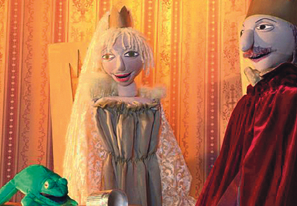 Auf einem Tisch sitzt ein Frosch, davor liegt die Krone. Daneben stehen König und Prinzessin.