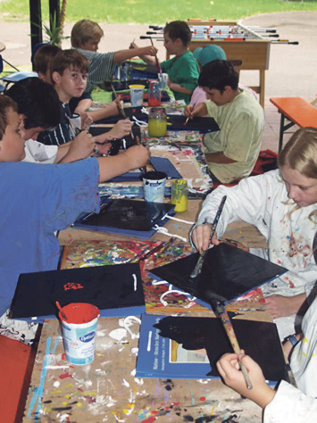 Kinder malen mit Pinsel und bunten Farben auf schwarzes Papier