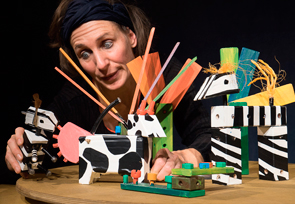 Frau sitz an einem Tisch und bewegt Tierfiguren hin und her.