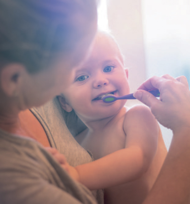 Eine Mutter putzt einem Kleinkind die Zähne.