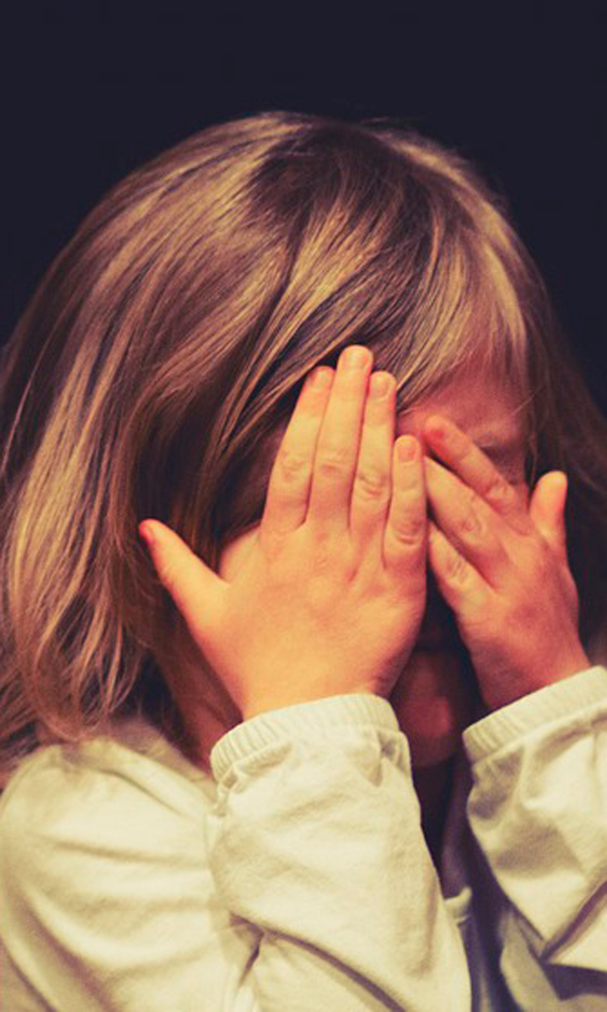 Kleines Mädchen hält sich zerweifelt, die Augen mit den Händen zu.