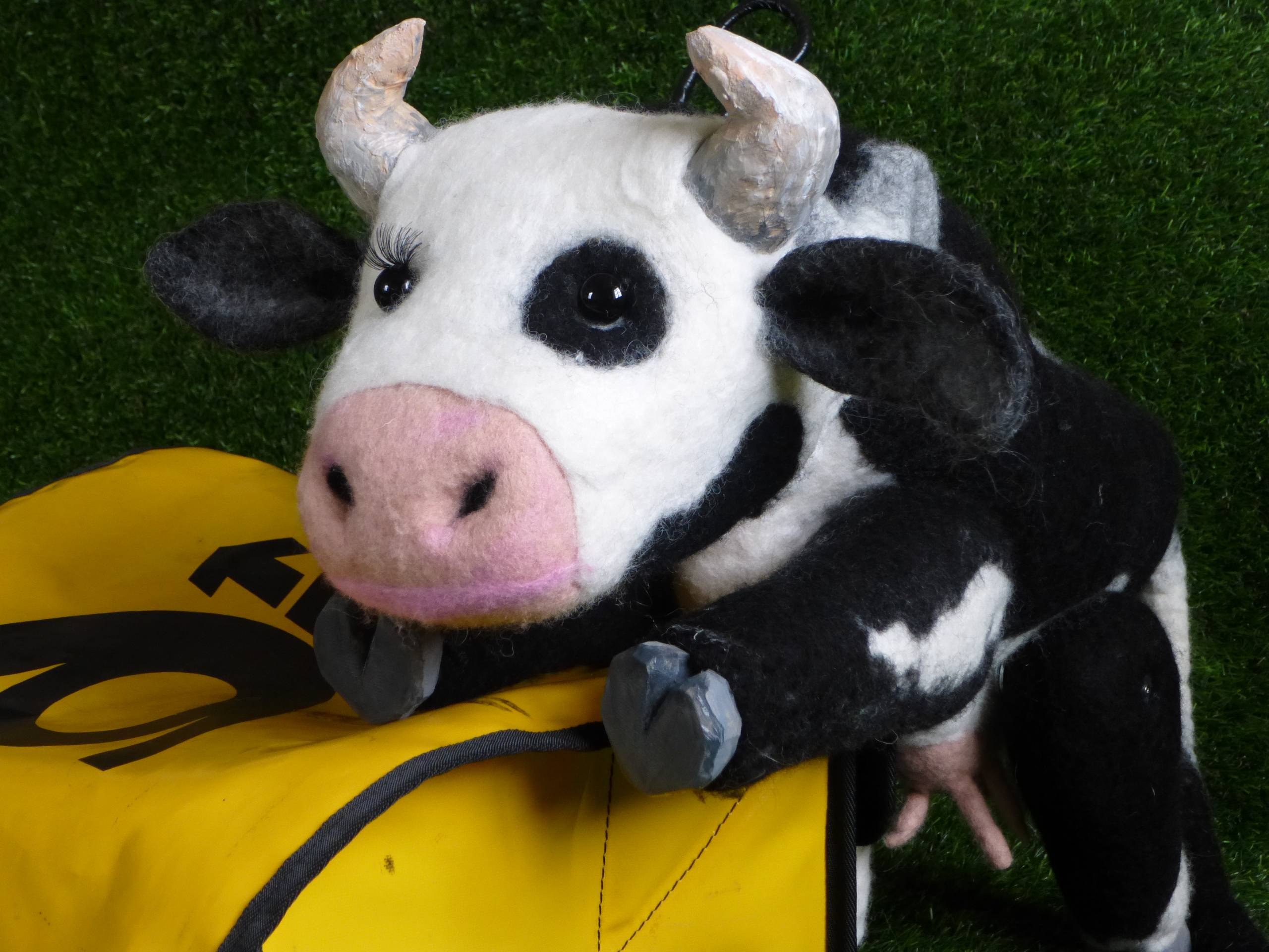 Eine Kuh-Puppe liegt auf einer Posttasche.