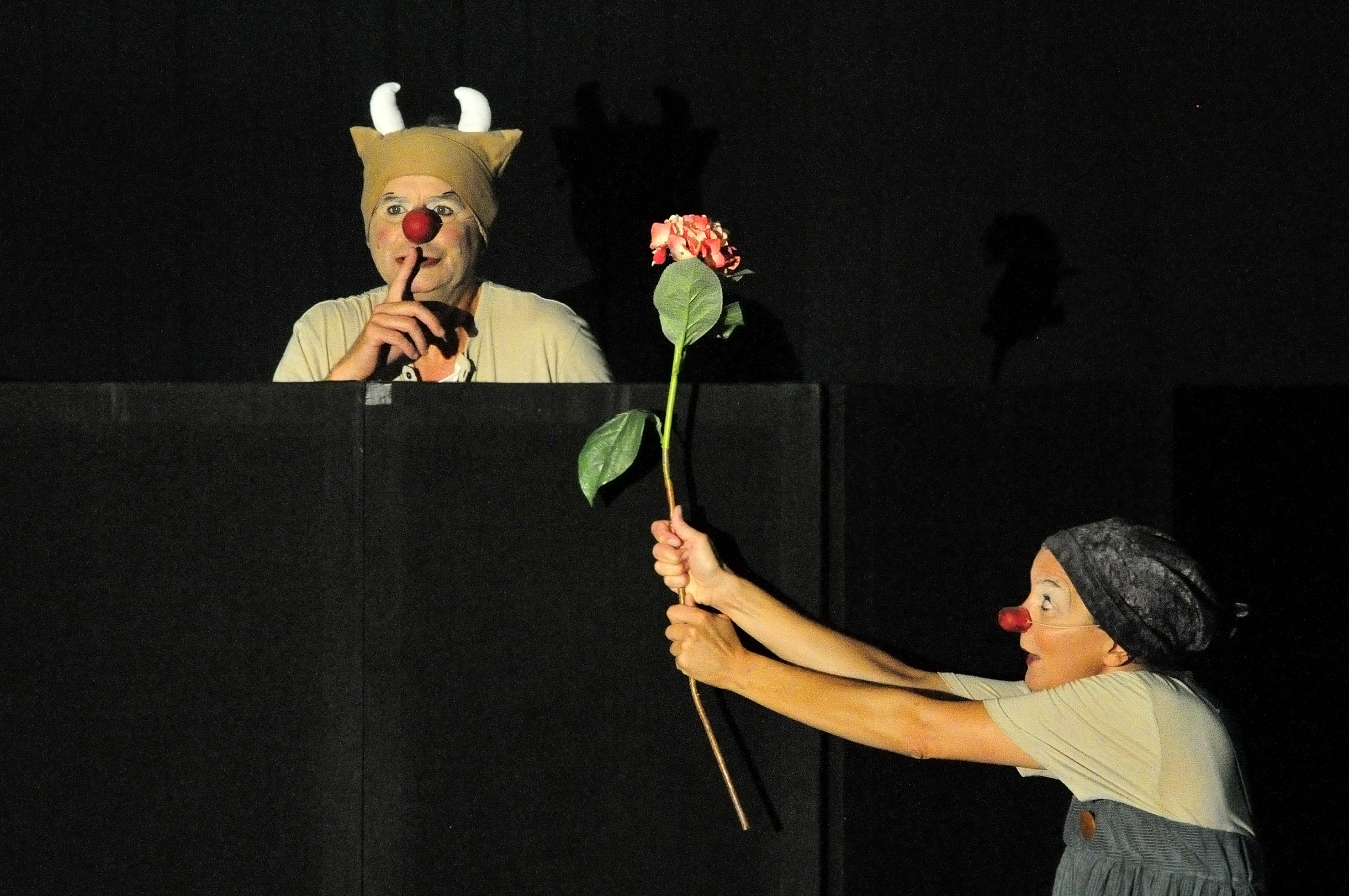 Eine Clownin überreicht einer Kuh eine Rose.