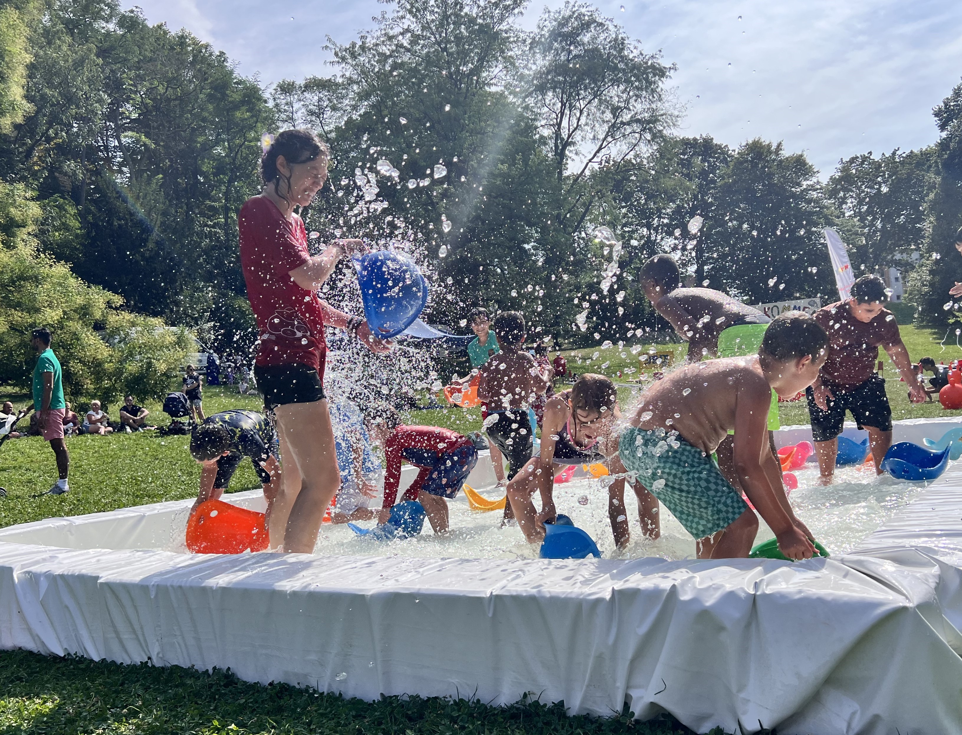 Kinder stehen in einem Minipool und bespritzen sich mit Wasser.