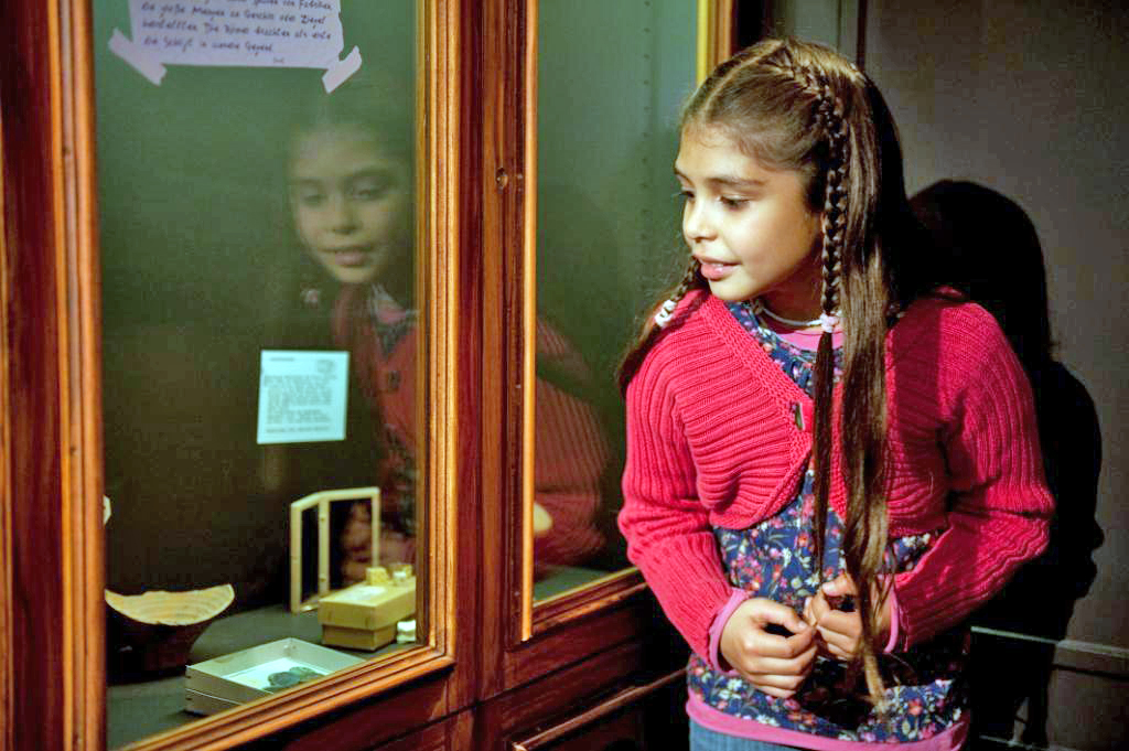 Mädchen schaut in eine Vitrine mit kleinen Ausstellungsstücken