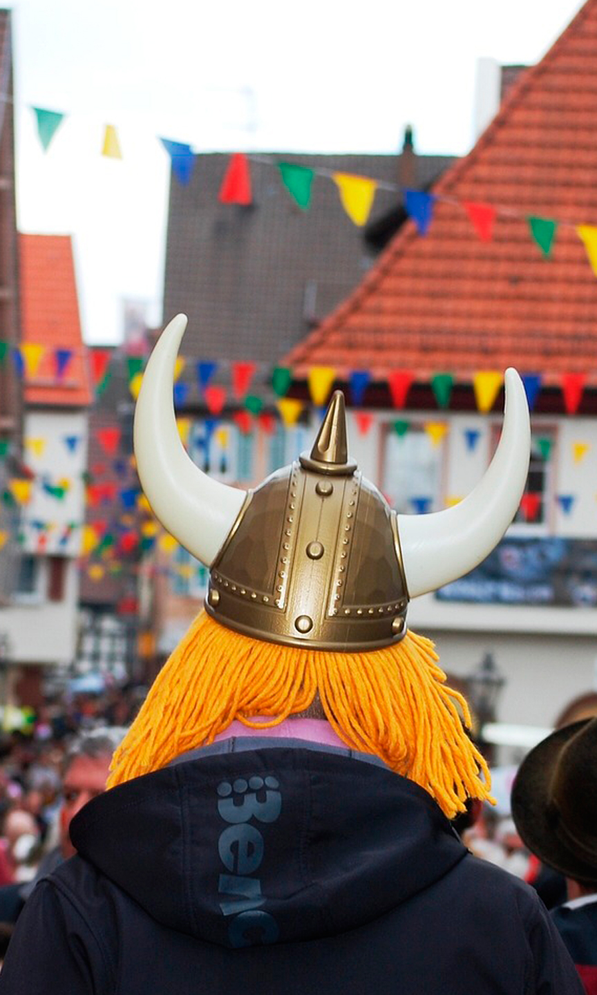 Man sieht einen Mann von hinten, der einen Wikinger-Helm trägt.