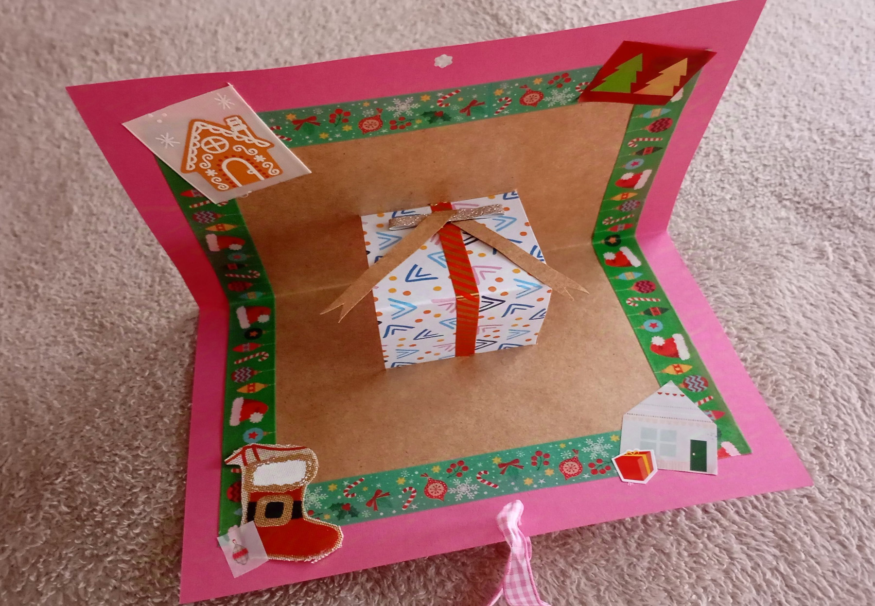 Eine gebastelte weinachtliche Pop-Up-Karte mit einem Geschenk in der Mitte