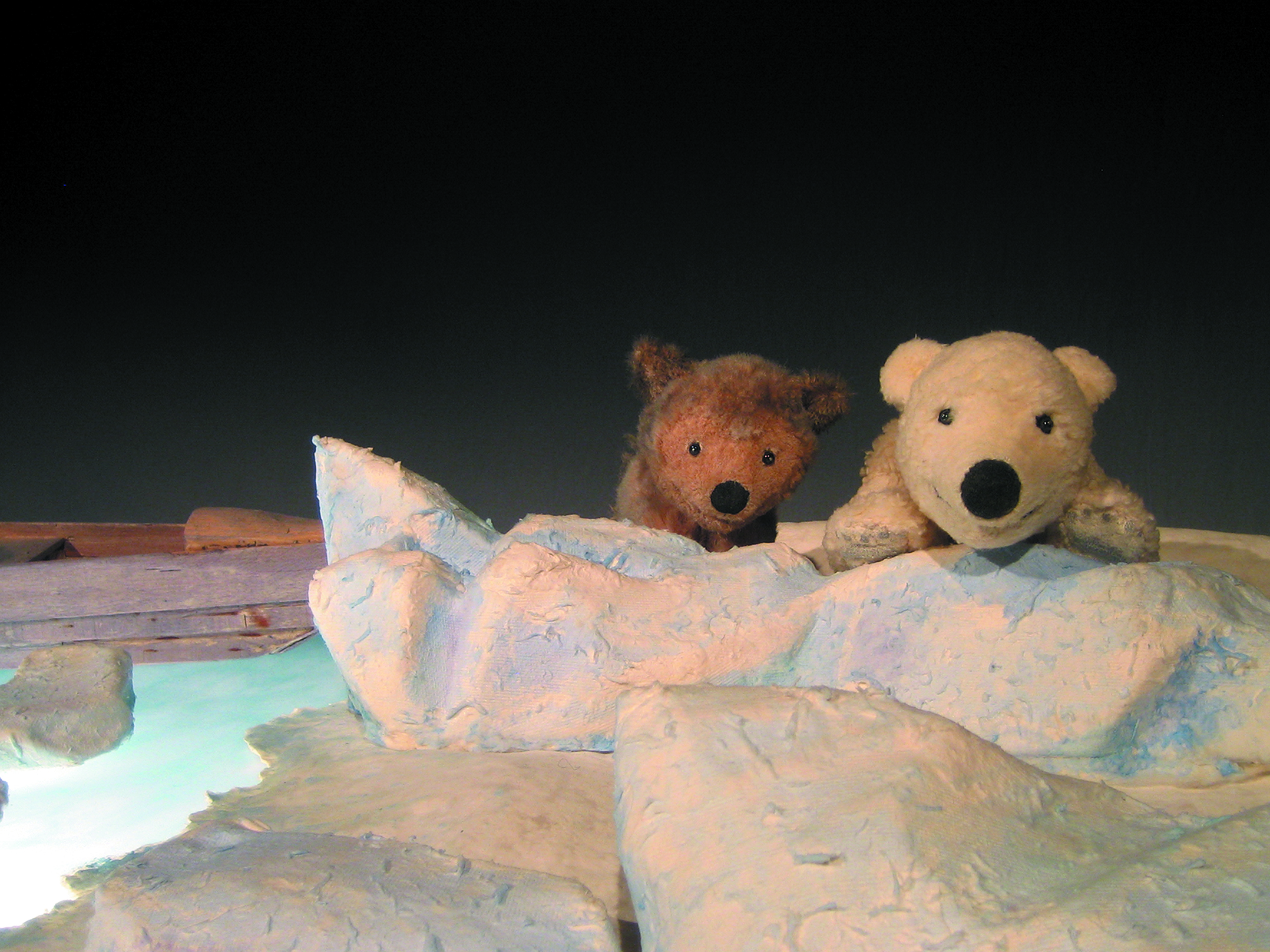 2 Theaterfiguren: ein brauner und ein weißer Bär liegen auf dem Eis