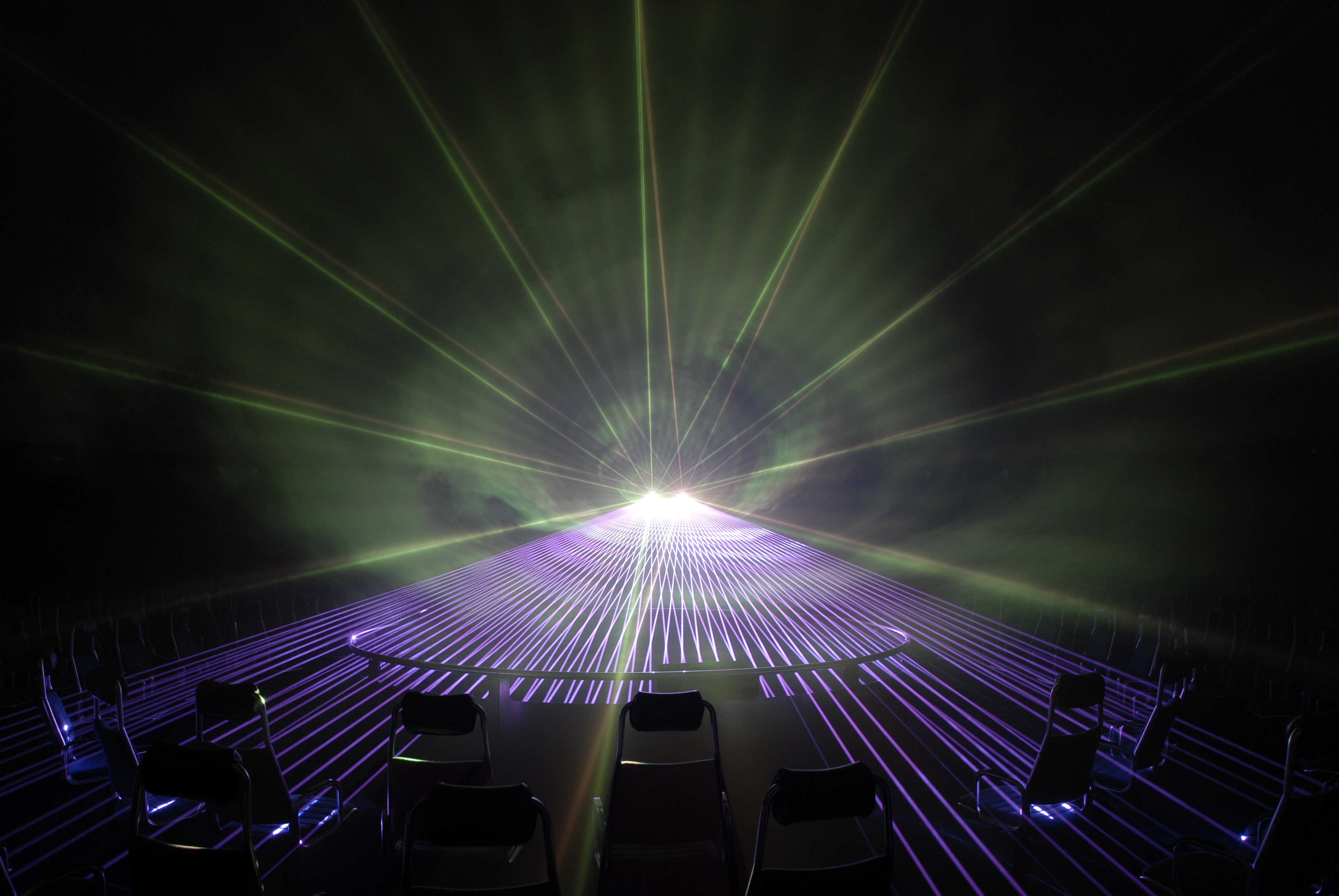 Rund um den Projektor des Planetariums erstrahlen bunte Laser