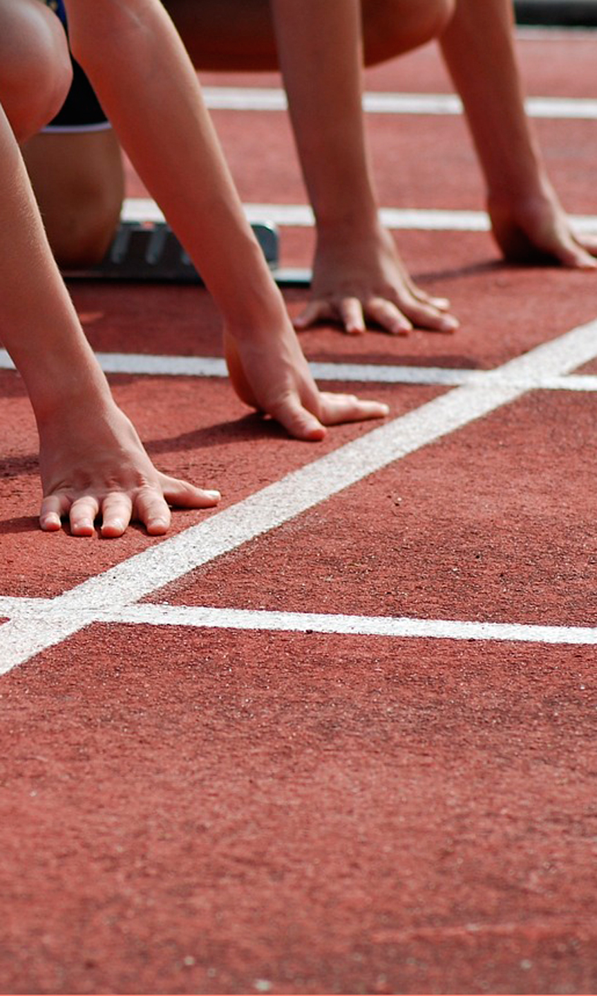 Läufer in Starthaltung auf der Tartanbahn bei Laufdisziplinen.