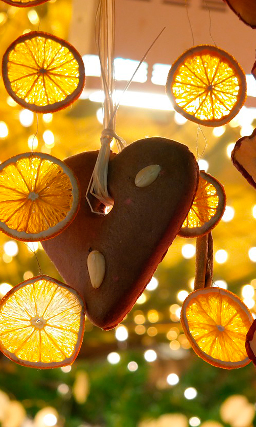 Ein Lebkuchenherz und eine Kette mit getrockneten Organgen an einem Marktstand.