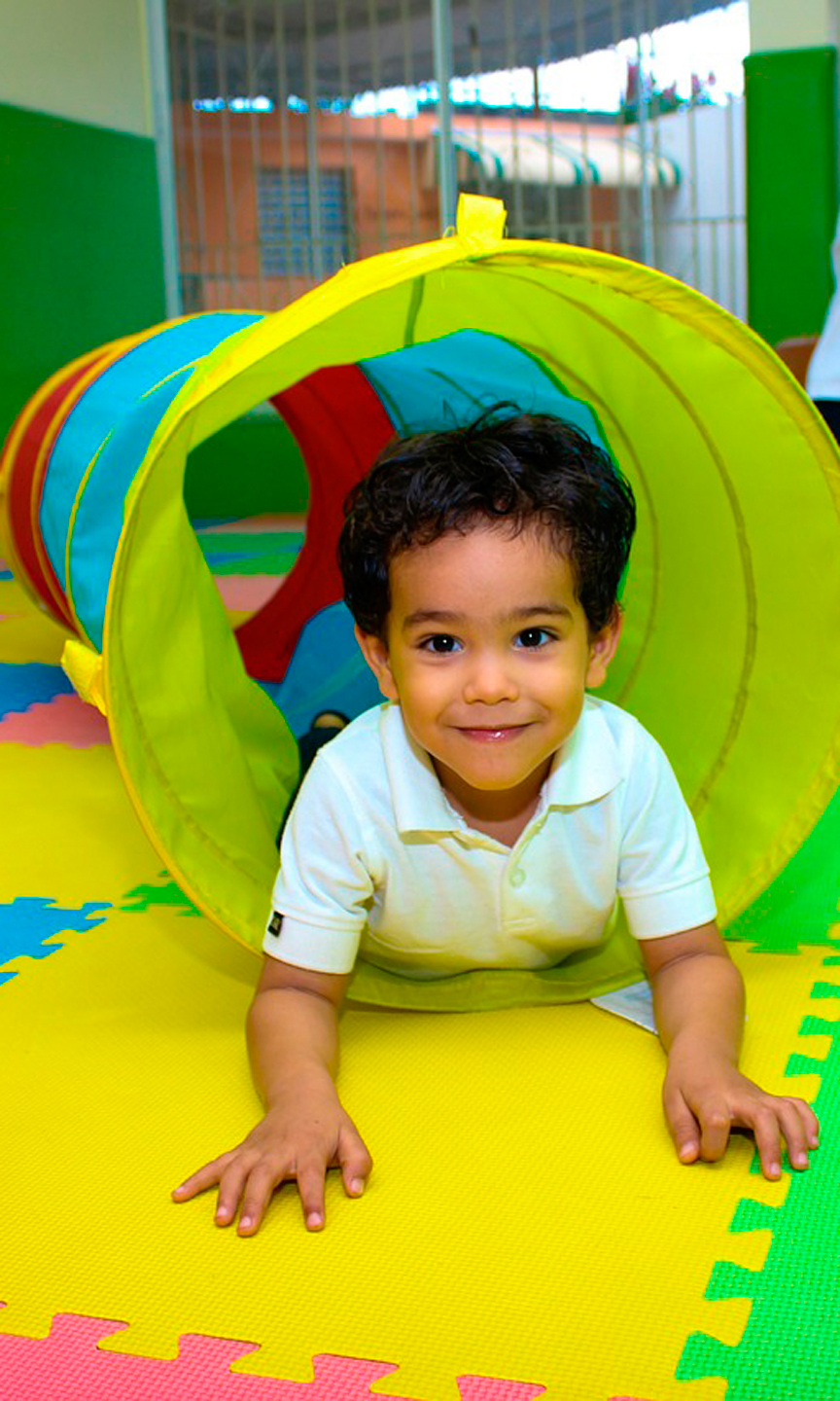 Kind krabelt über den Boden durch eine Röhre.