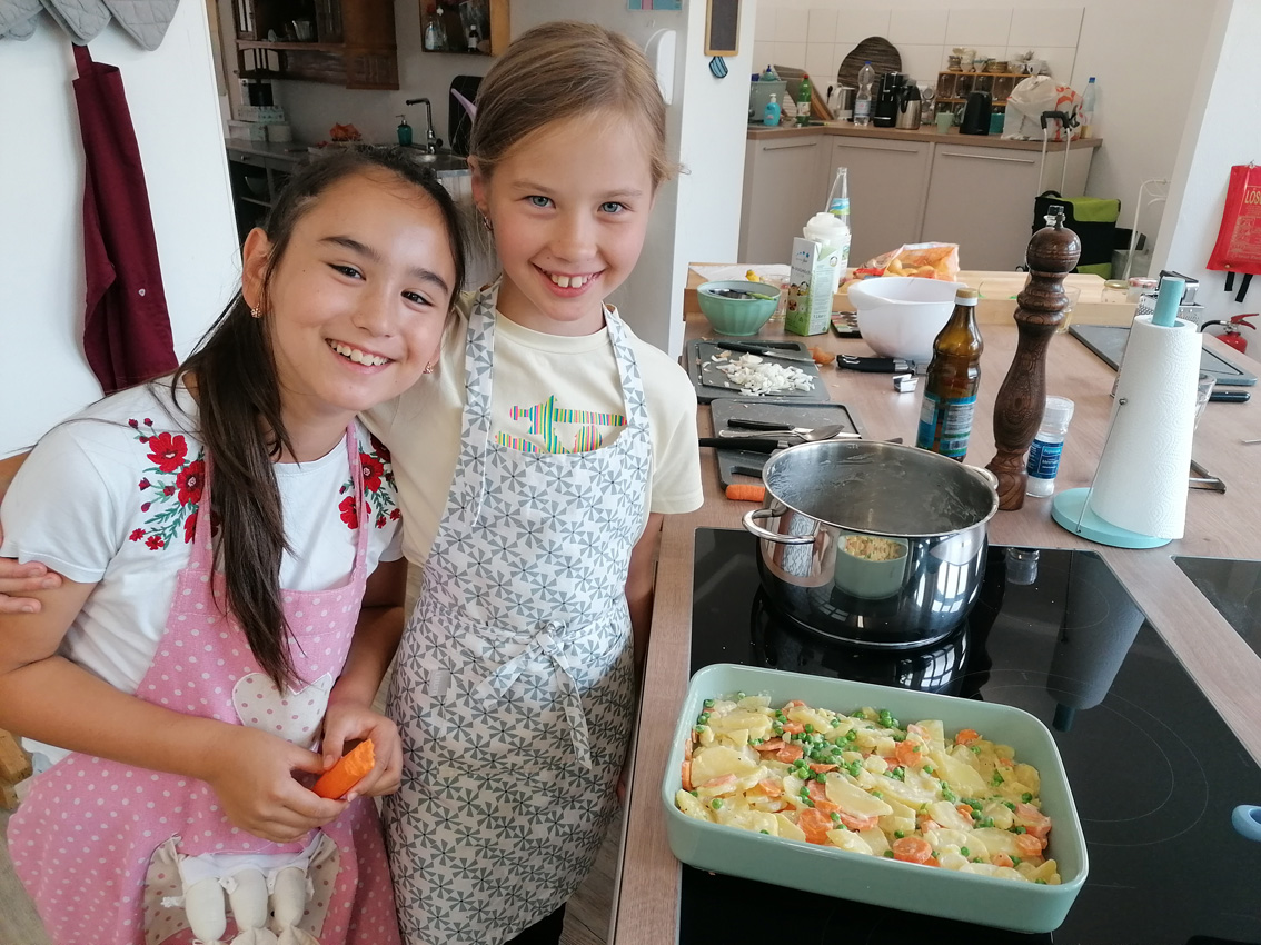 2 Mädchen in der Küche vor einem gemüse-Auflauf