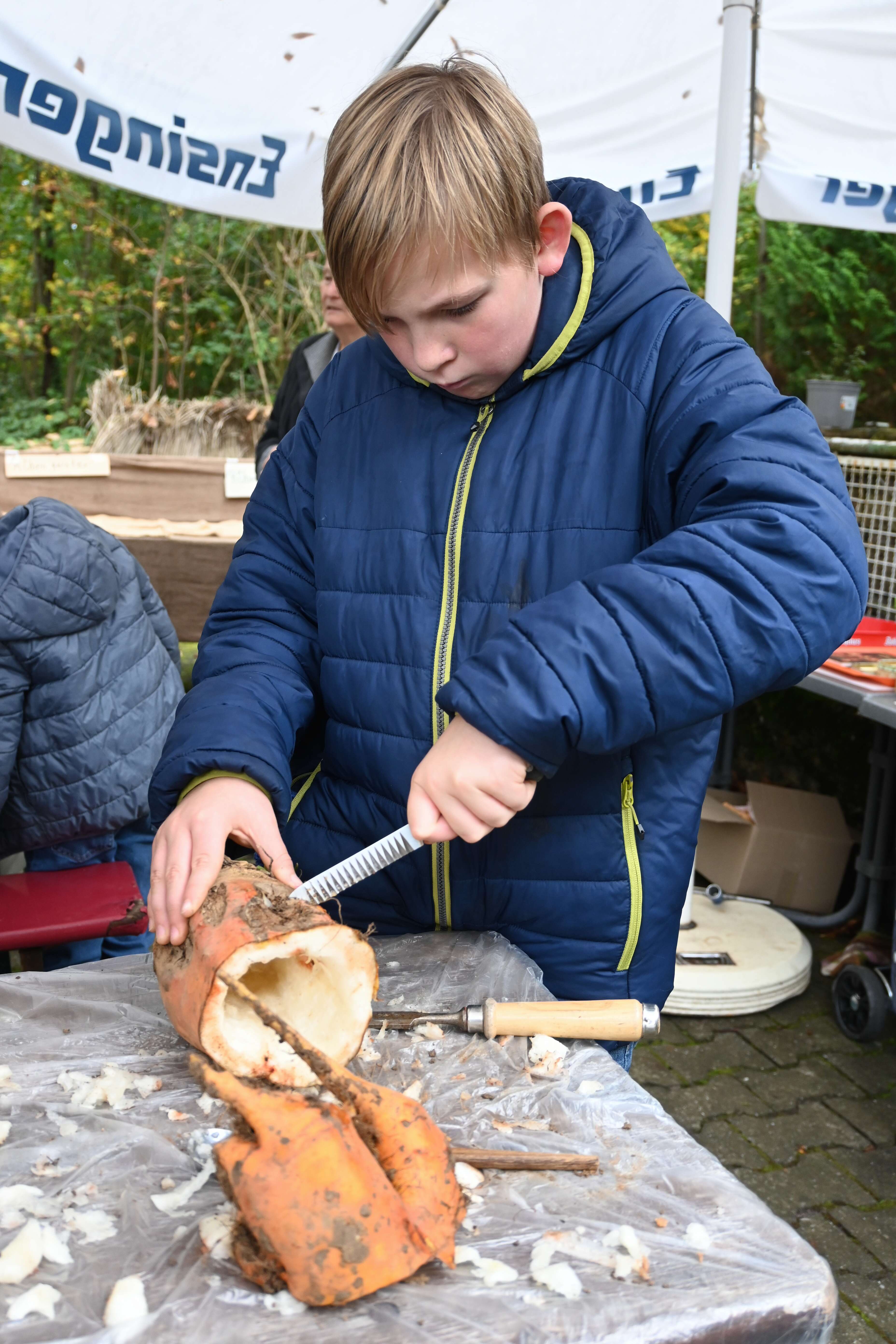 Ein Junge schnitzt eine Rübe.