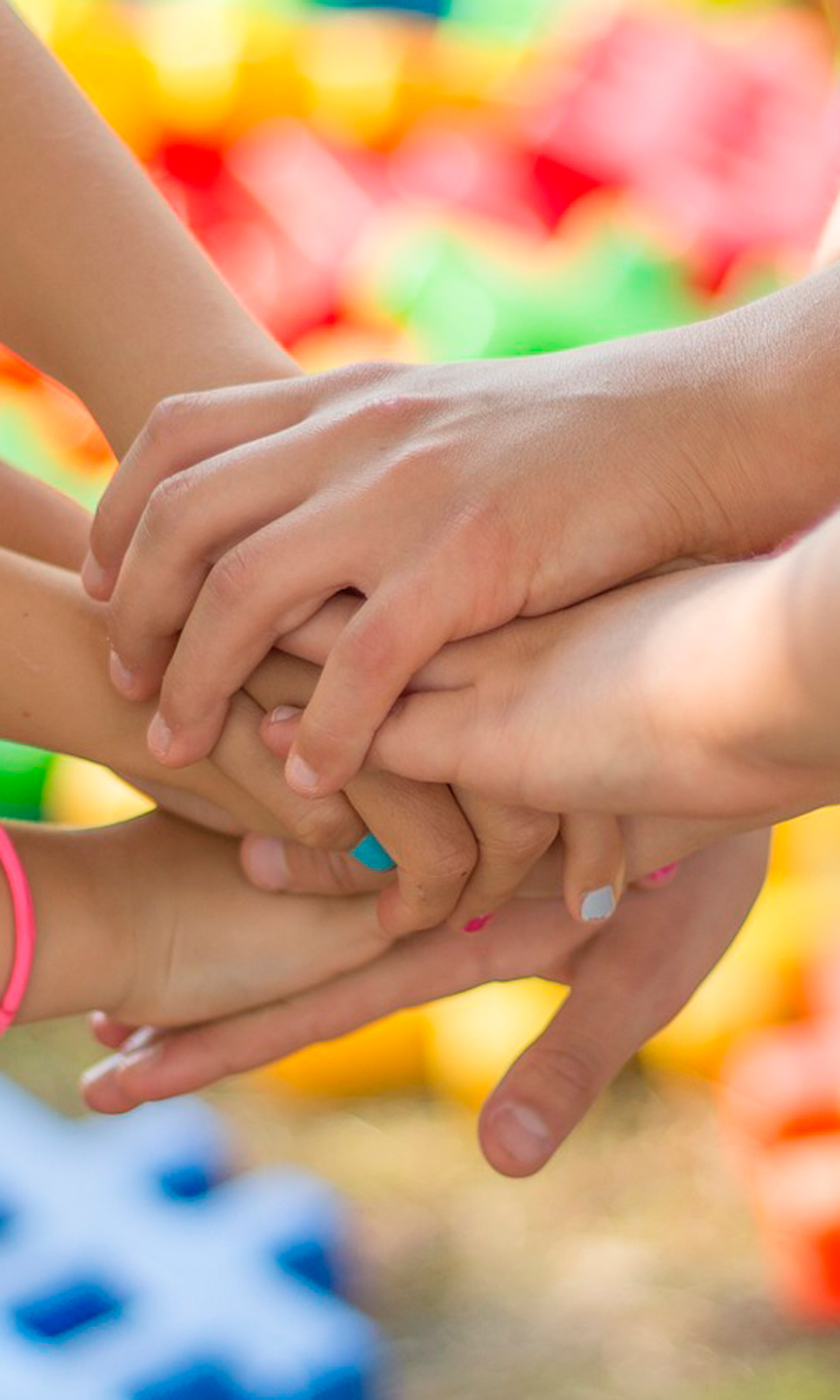 Mehrere Kinderhände liegen aufeinander.