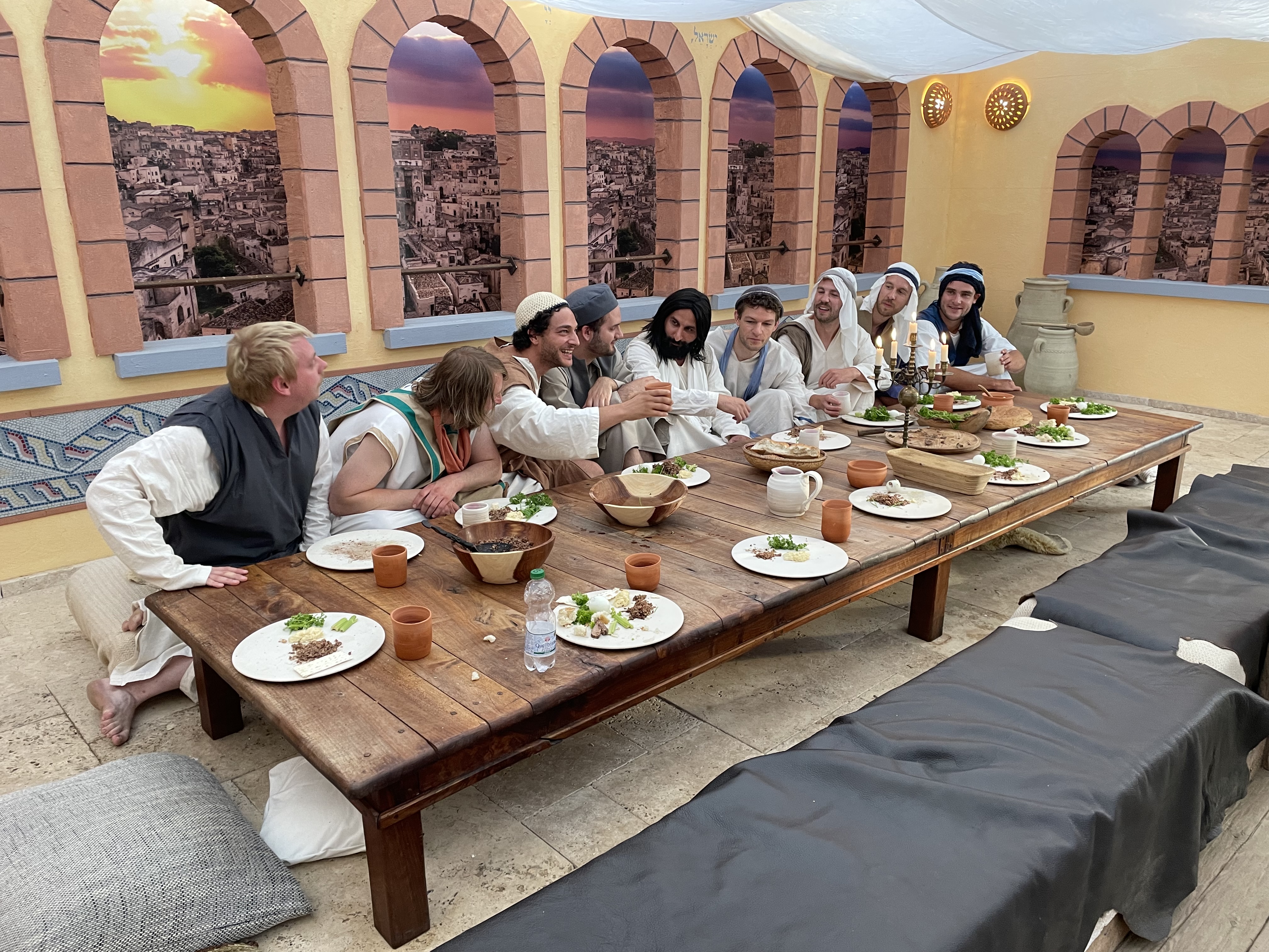 Schauspieler sitzen an einem Tisch und stellen das Abendmahl dar