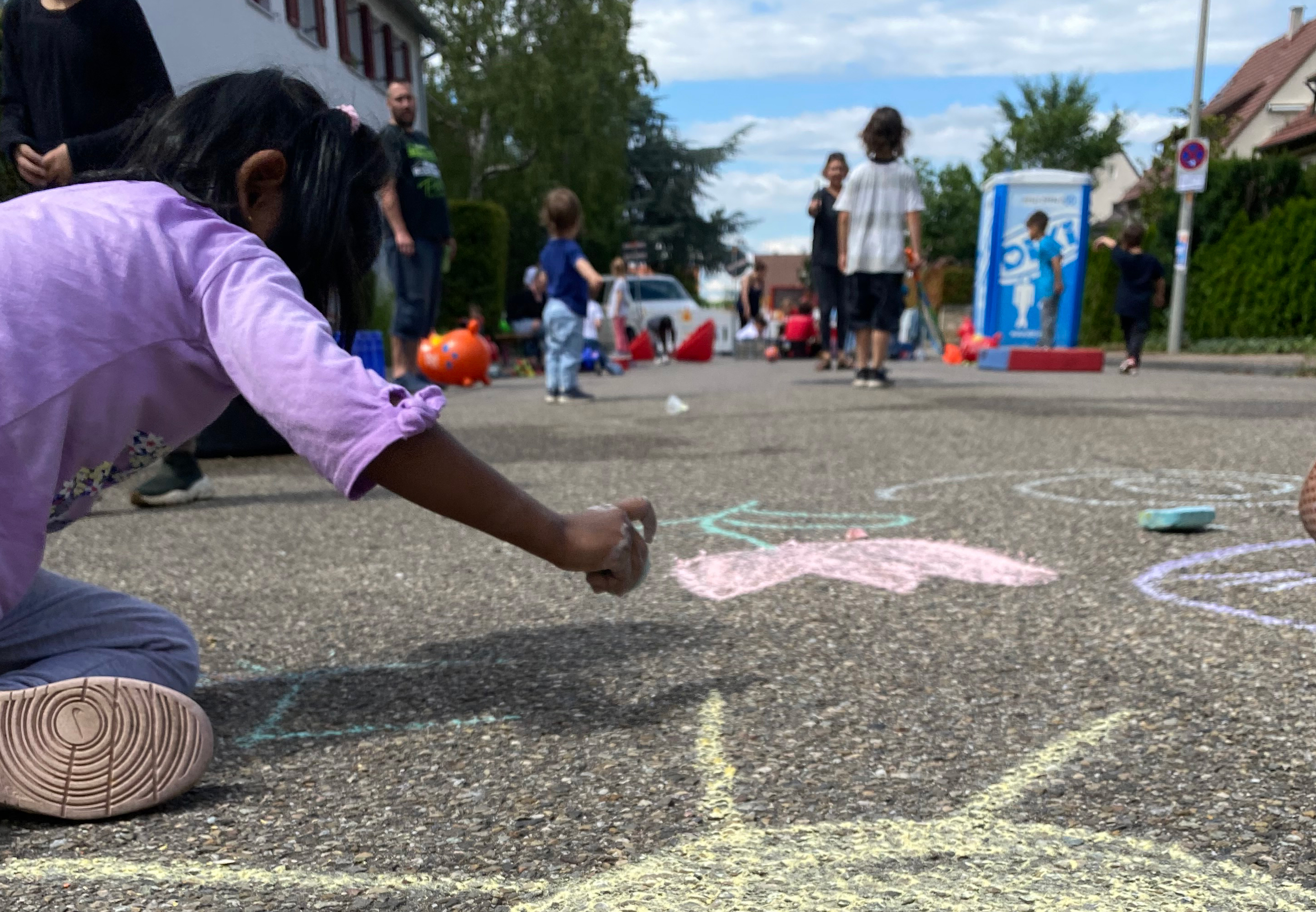 Kinder bemalen eine Straße mit Kreide und spielen.