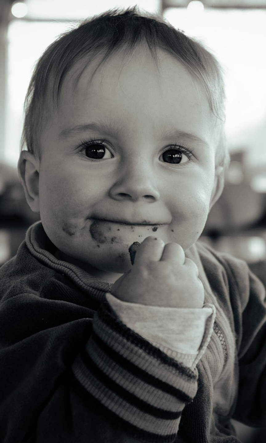 Schwarz-weiß Bild. Kleinkind ißt mit den Händen.