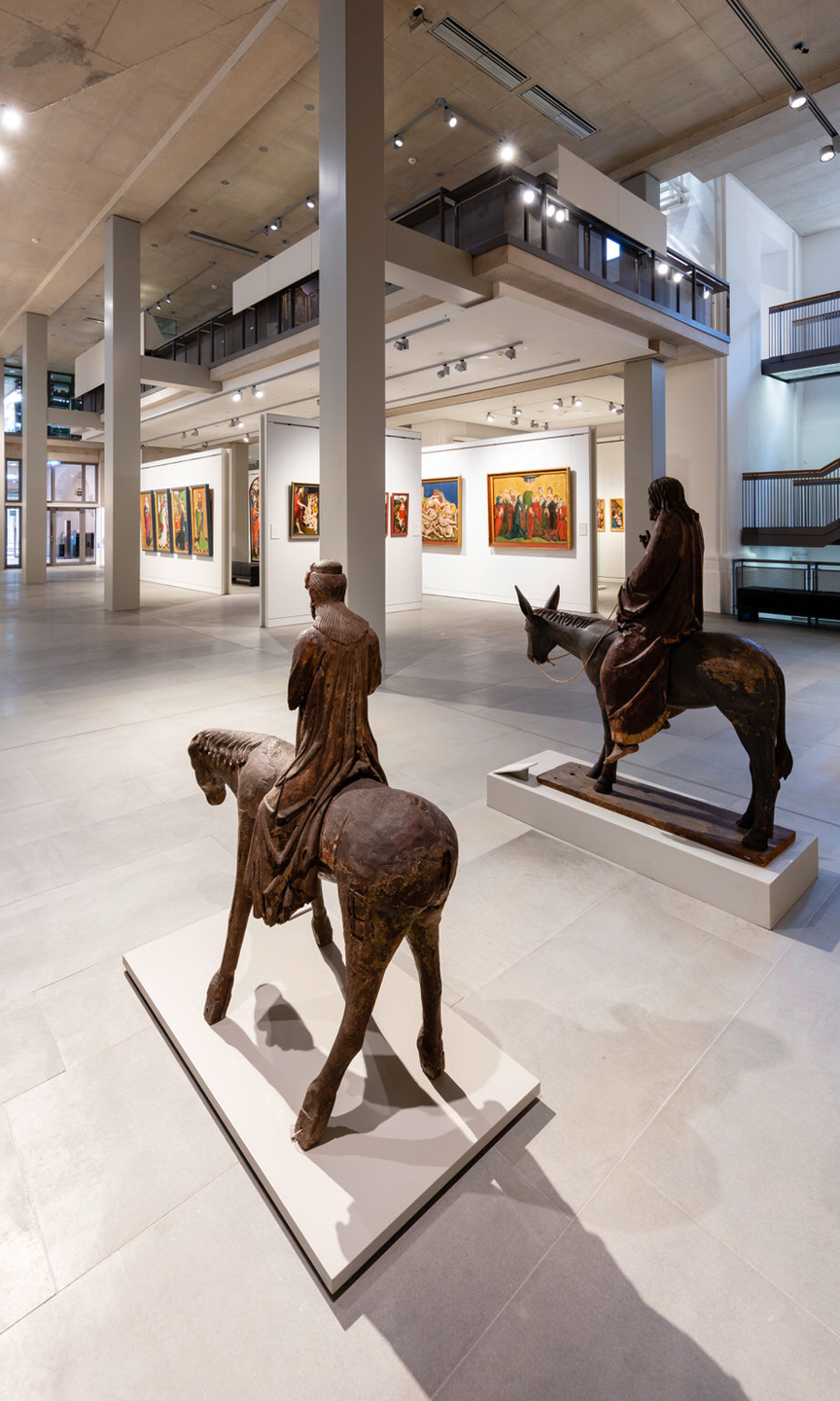Innenraum des Diözesenmuseum Rottenburg. Reiterstatuen stehen im Raum und Bilder hängen an der Wand.