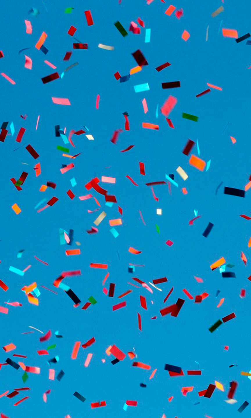 Buntes Konfetti fliegt durch einen blauen Himmel