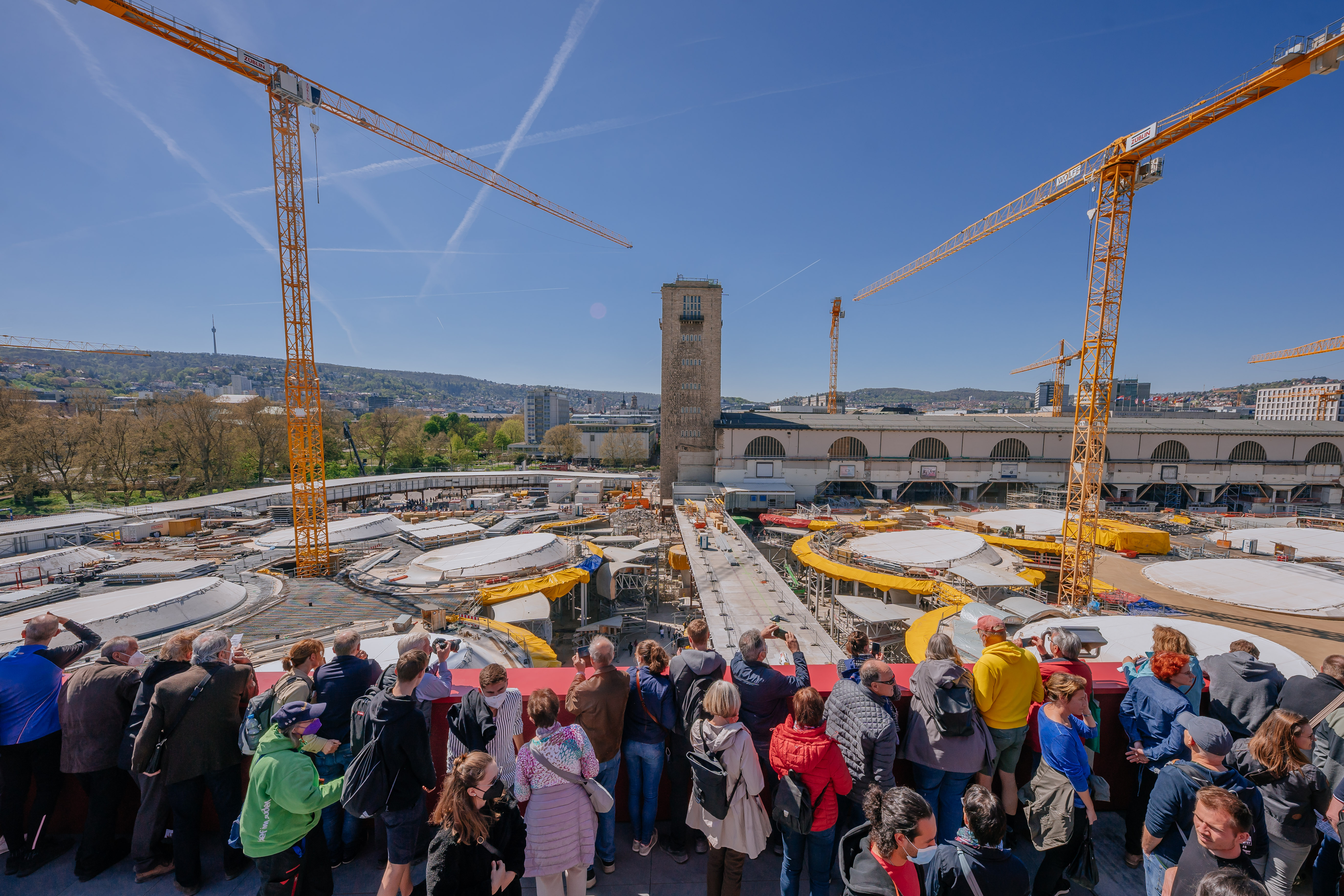 Menschen stehen auf einer Erhöhung und schauen auf die Baustelle vom Bahnprojekt Stuttgart 21